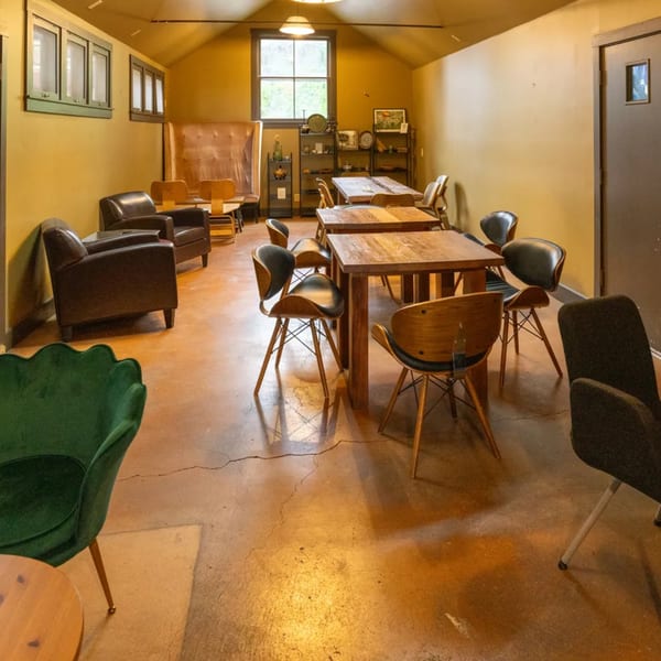 Cozy restaurant interior with various seating arrangements, including wooden tables, chairs, and armchairs.
